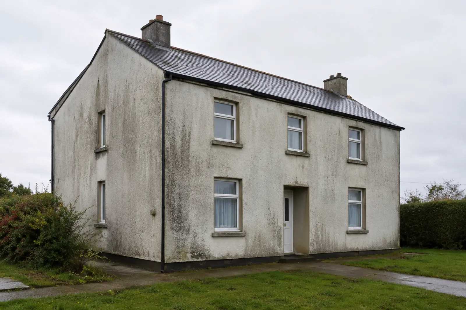 Solid-wall house with tired cracked render before external wall insulation